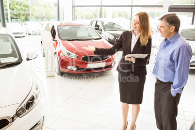 Smiling businesswoman showing car to customer