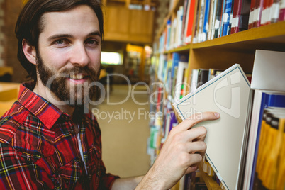 Happy student picking book in library
