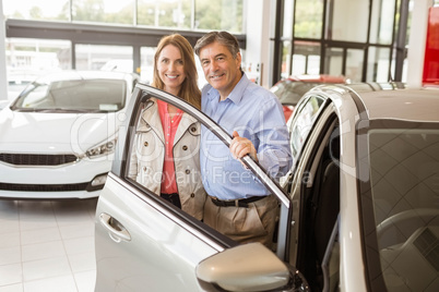 Smiling couple leaning on car