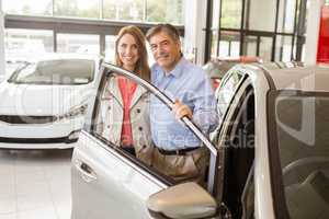 Smiling couple leaning on car