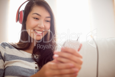 Smiling asian woman on couch listening to music