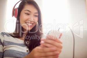 Smiling asian woman on couch listening to music