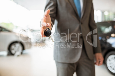 Salesman standing while offering car keys