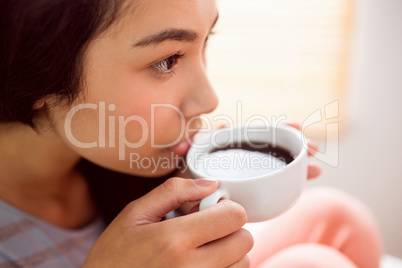 Asian woman relaxing on couch with coffee