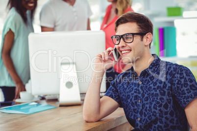 Smiling creative businessman working near co workers