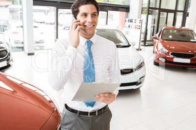 Smiling businessman on the phone holding clipboard