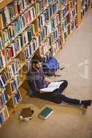 Student reading book in library on floor