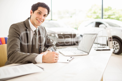 Smiling salesman behind his desk