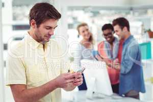 Creative businessman using smartphone in front of colleagues