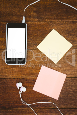 Post it and black smartphone with white headphones