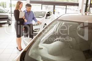 A man showing a car to the saleswoman