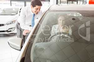 Businessman leaning on door showing car to customer