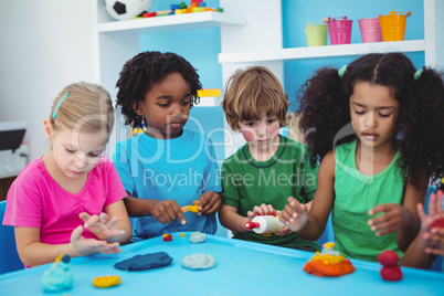 Smiling kids playing with modelling clay