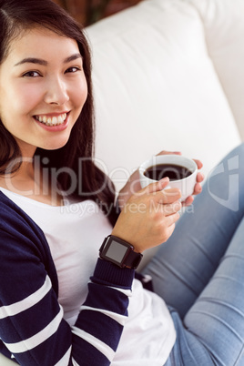 Asian woman relaxing on couch with coffee