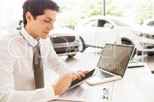 Smiling salesman using tablet at his desk