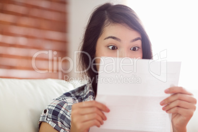 Asian woman on the couch reading letter