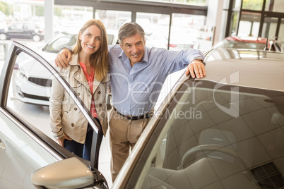 Smiling couple leaning on car