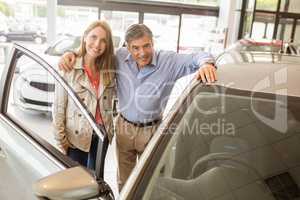 Smiling couple leaning on car