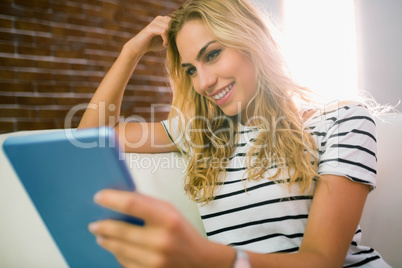 Pretty blonde using tablet on couch