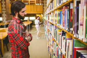 Hipster student picking a book in library