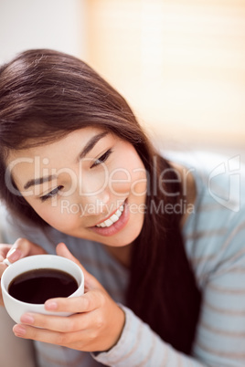 Asian woman relaxing on couch with coffee