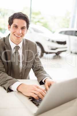 Smiling salesman typing on his laptop Smiling salesman typing on his laptop