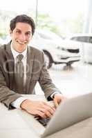 Smiling salesman typing on his laptop