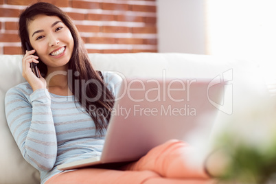 Asian woman on the phone using laptop