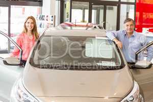 Smiling couple leaning on car