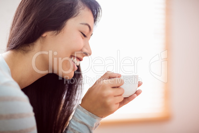 Asian woman relaxing on couch with coffee