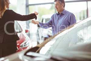 Saleswoman giving car keys while shaking hand of a client