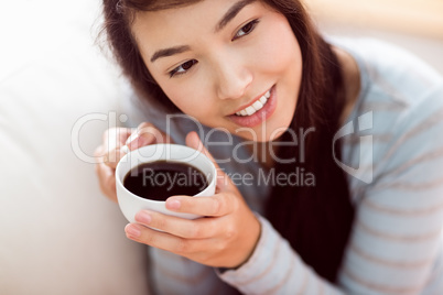 Asian woman relaxing on couch with coffee