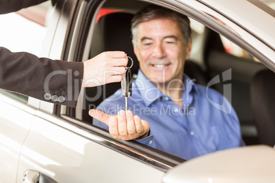 Salesman giving keys to a smiling businessman