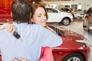 Smiling woman holding key while hugging her husband