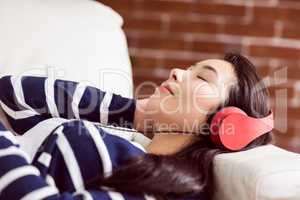 Asian woman lying on the couch listening to music