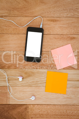 post it and black smartphone with white headphones