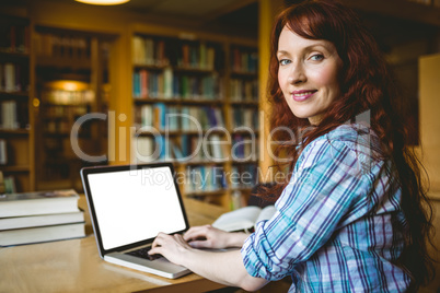 Mature student studying in library with laptop