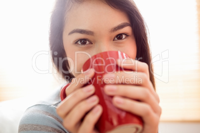 Asian woman relaxing on couch with coffee