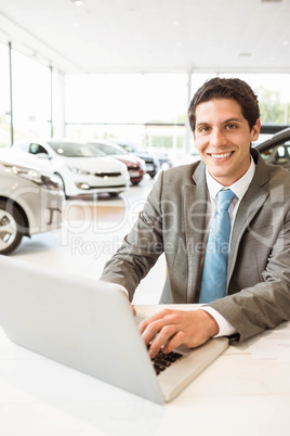 Smiling salesman writing on his laptop