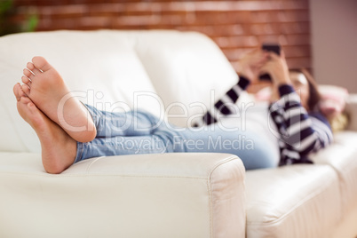 Asian woman lying on the couch using phone