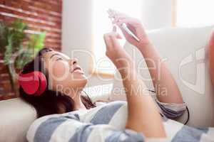 Smiling asian woman on couch listening to music