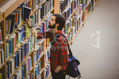 Student picking a book from shelf in library