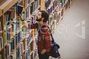 Student picking a book from shelf in library