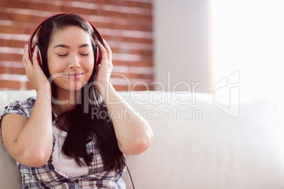 Asian woman on the couch listening to music