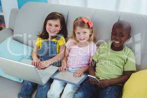 Happy kids sitting together with a tablet and laptop and phone