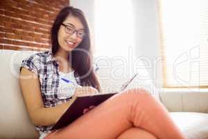 Asian woman on the couch writing