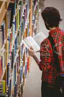 Student picking a book from shelf in library