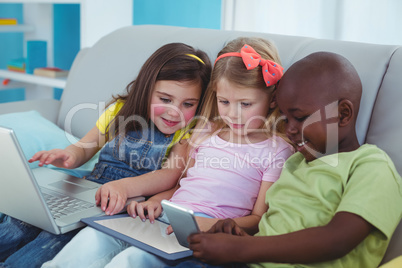 Happy kids sitting together with a tablet and laptop and phone