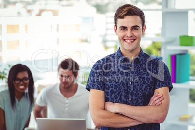 Smiling creative businessman working near co workers