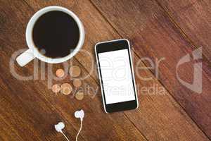View of a white smartphone with a cup of coffee